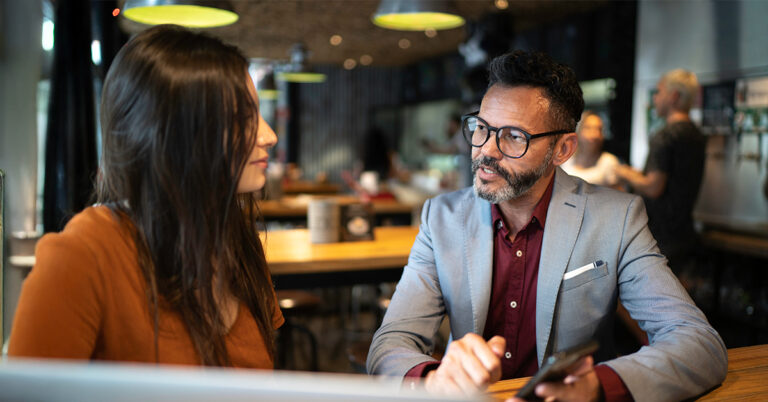 Restaurant workers collaborating and reviewing resources at café table