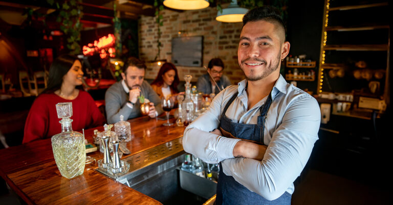 Bartender standing confidently behind bar after renewing MAST permit