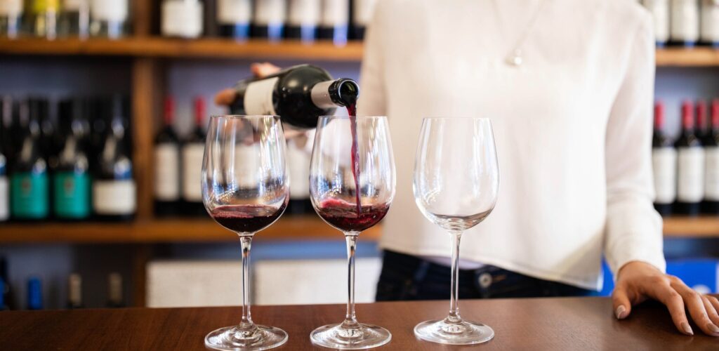 Washington minor server pouring red wine at winery a winery counter