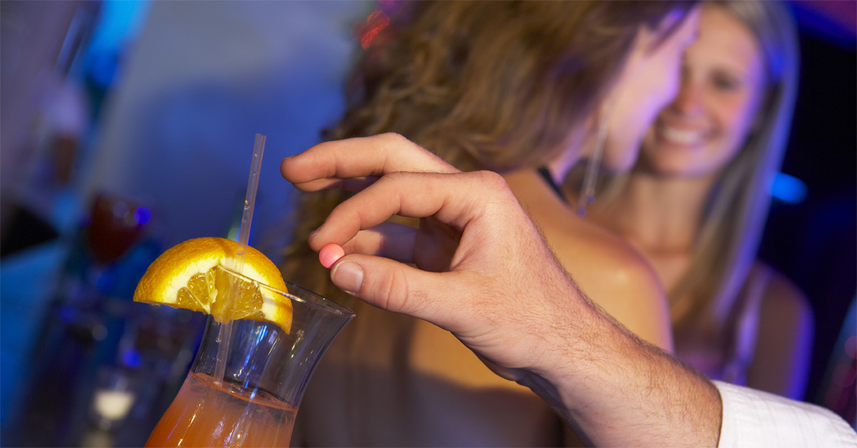 California drink spiking law addresses risks like this: a man secretly drops a pill into a woman's cocktail at a dimly lit bar while she talks with a friend, unaware.